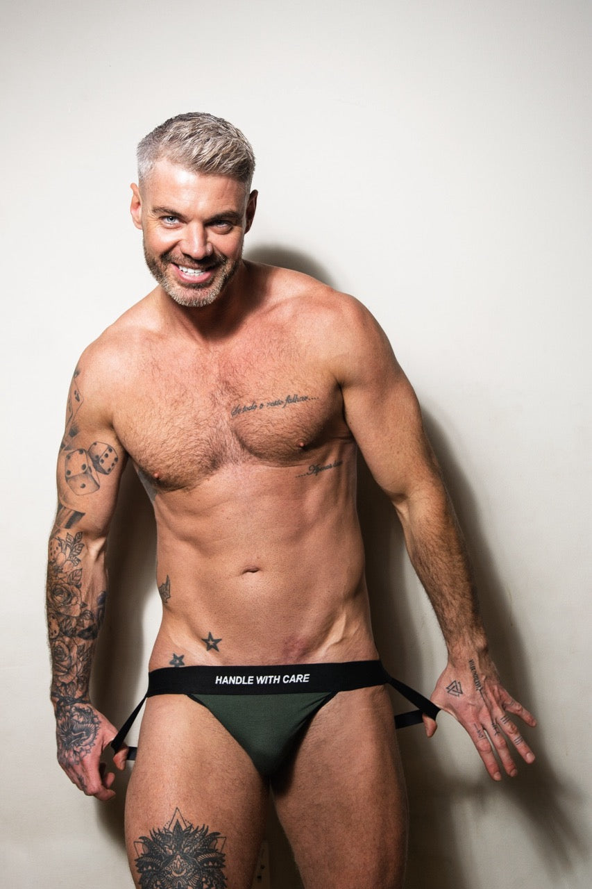 Handsome blond man wearing a gay jockstrap with Handle with Care waistband 